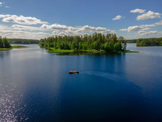 A paddler crossing a deep blue lake towards a wooded island