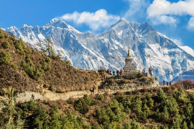 A white stupa with prayer flags below the snowy peaks of the Everest region